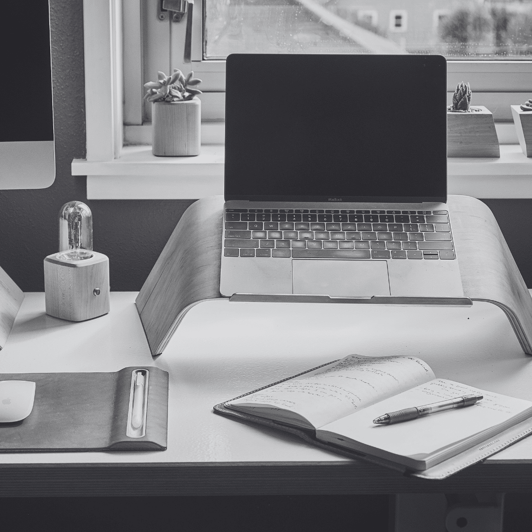 laptop on desk with notebook and pen